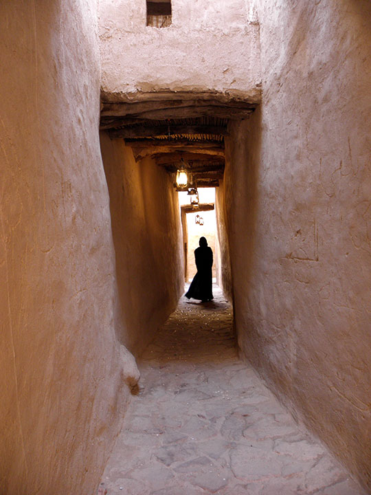 A woman in silhouette down a narrow corridor.